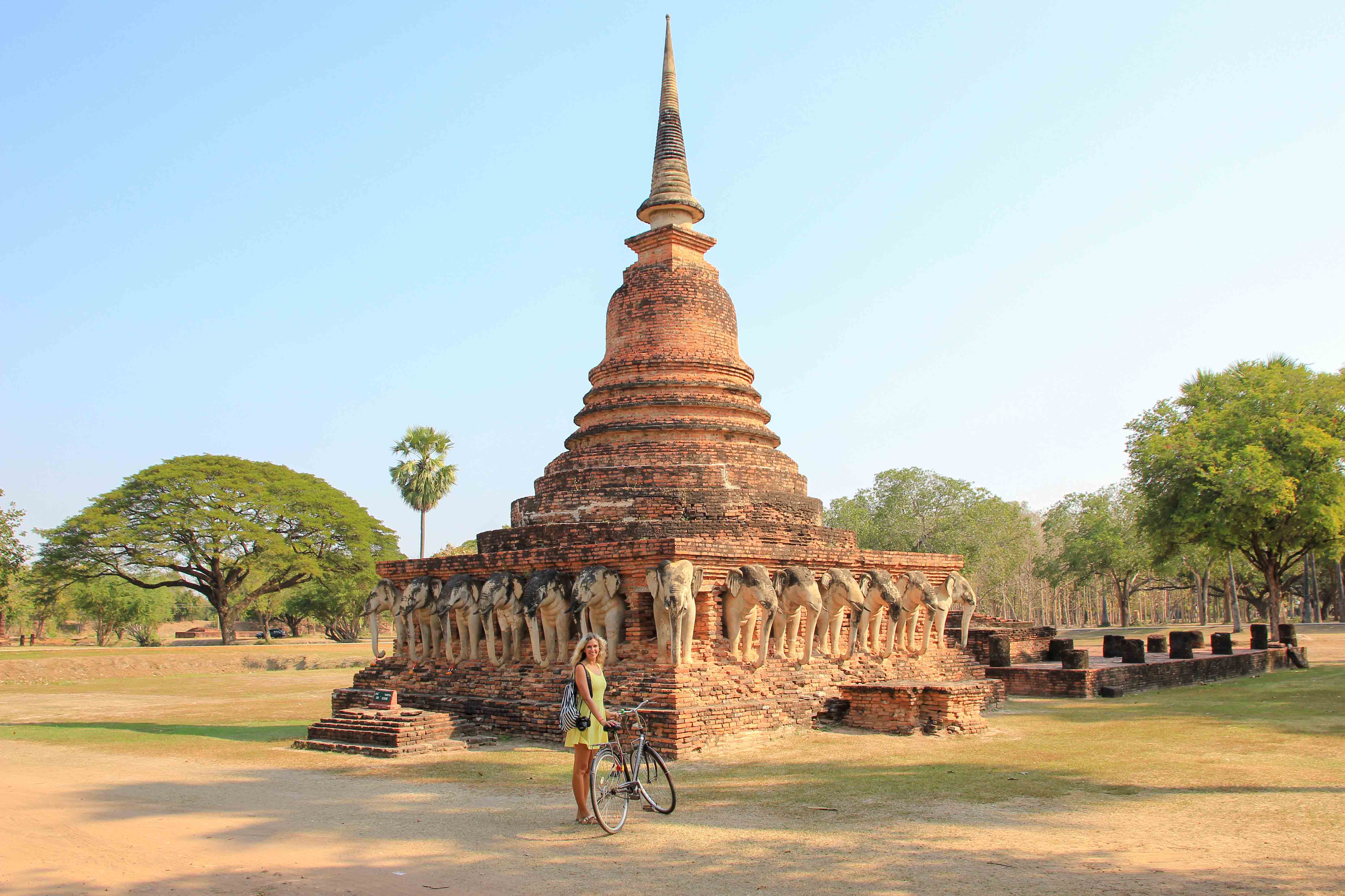 Young woman hipster backpacker traveling into Wat Mahathat temple in the  Sukhothai Historical Park contains the ruins of old Sukhothai, Thailand,  UNESCO world Heritage Site. Stock Photo