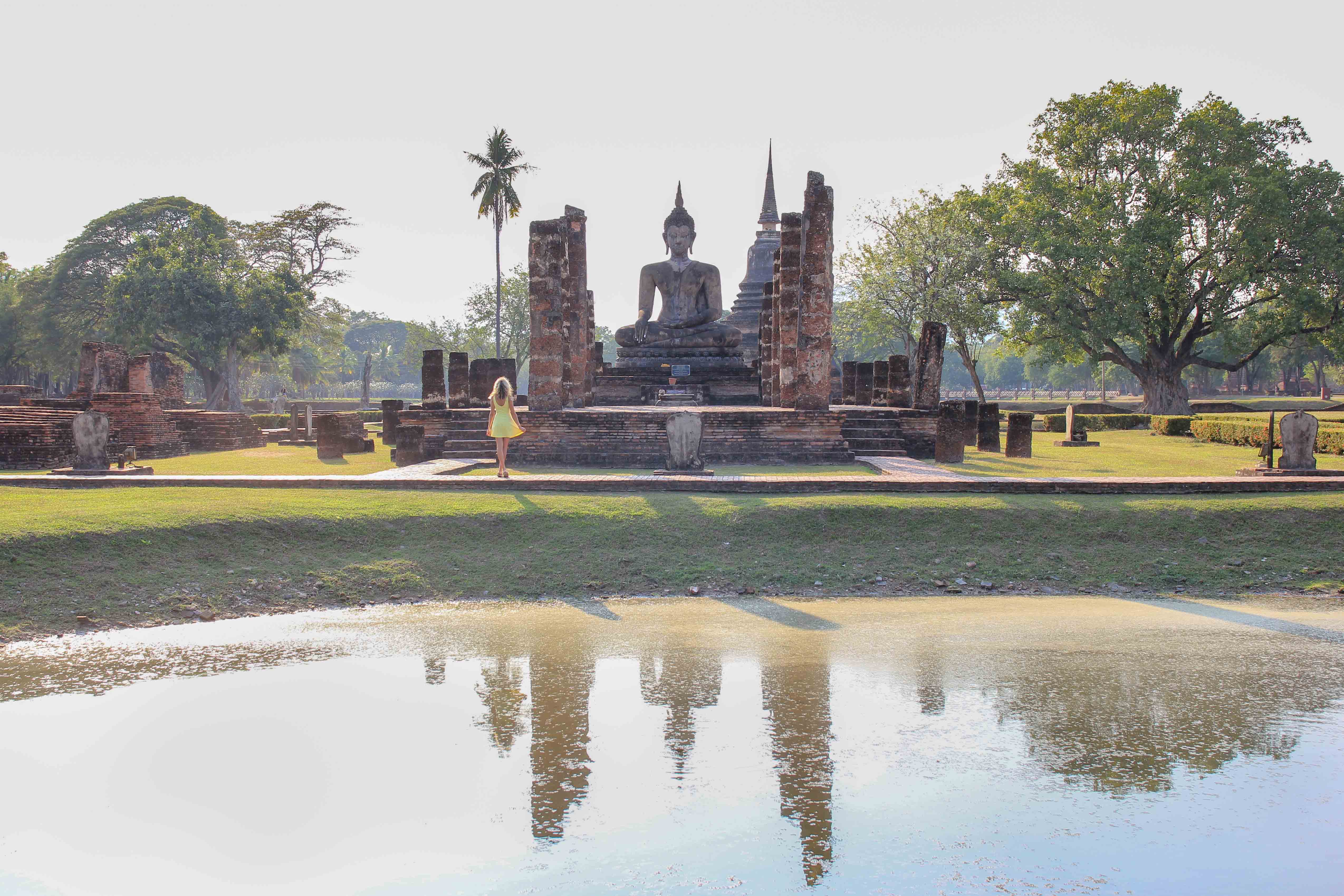 Young woman hipster backpacker traveling into Wat Mahathat temple in the  Sukhothai Historical Park contains the ruins of old Sukhothai, Thailand,  UNESCO world Heritage Site. Stock Photo