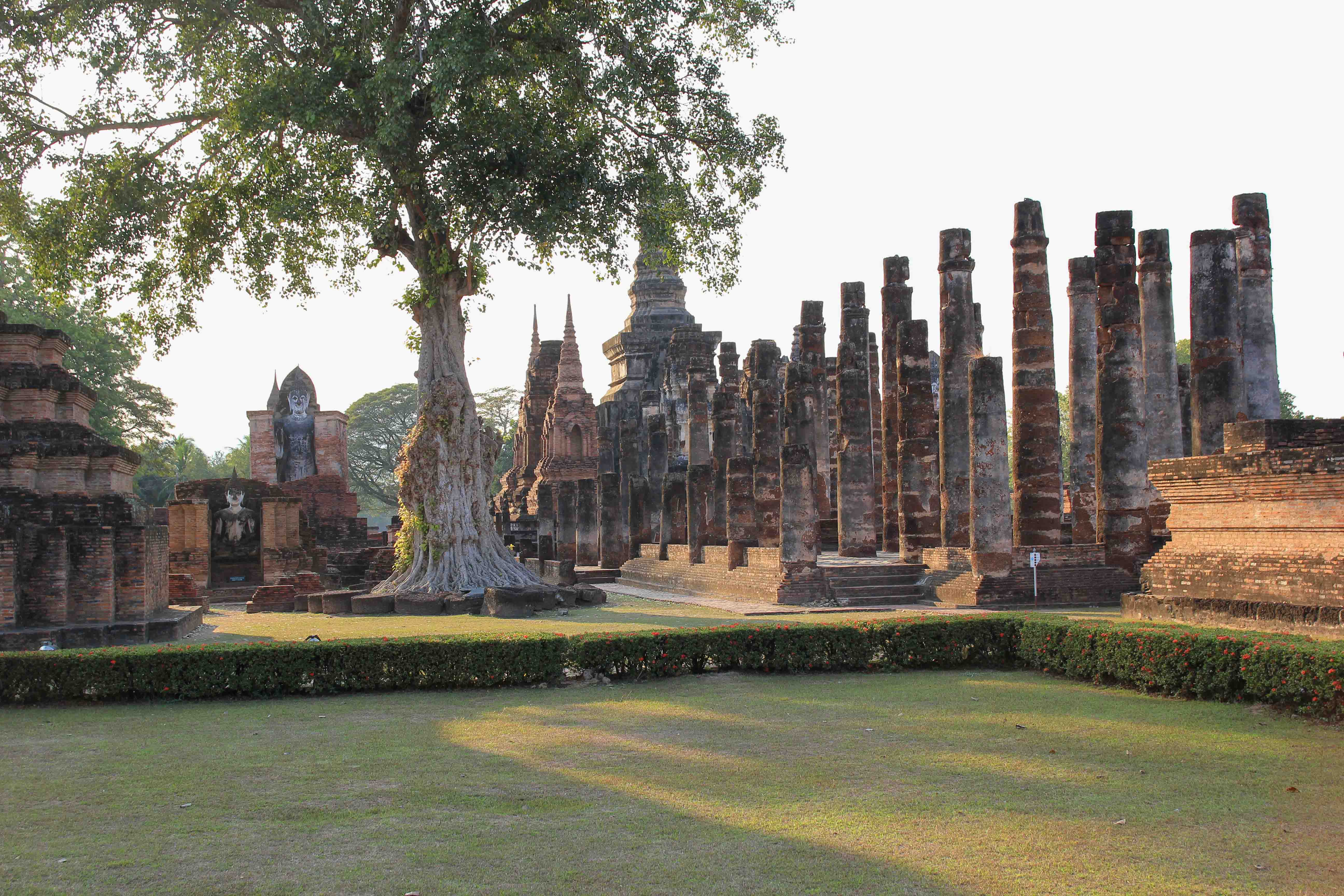 Young woman hipster backpacker traveling into Wat Mahathat temple in the  Sukhothai Historical Park contains the ruins of old Sukhothai, Thailand,  UNESCO world Heritage Site. Stock Photo