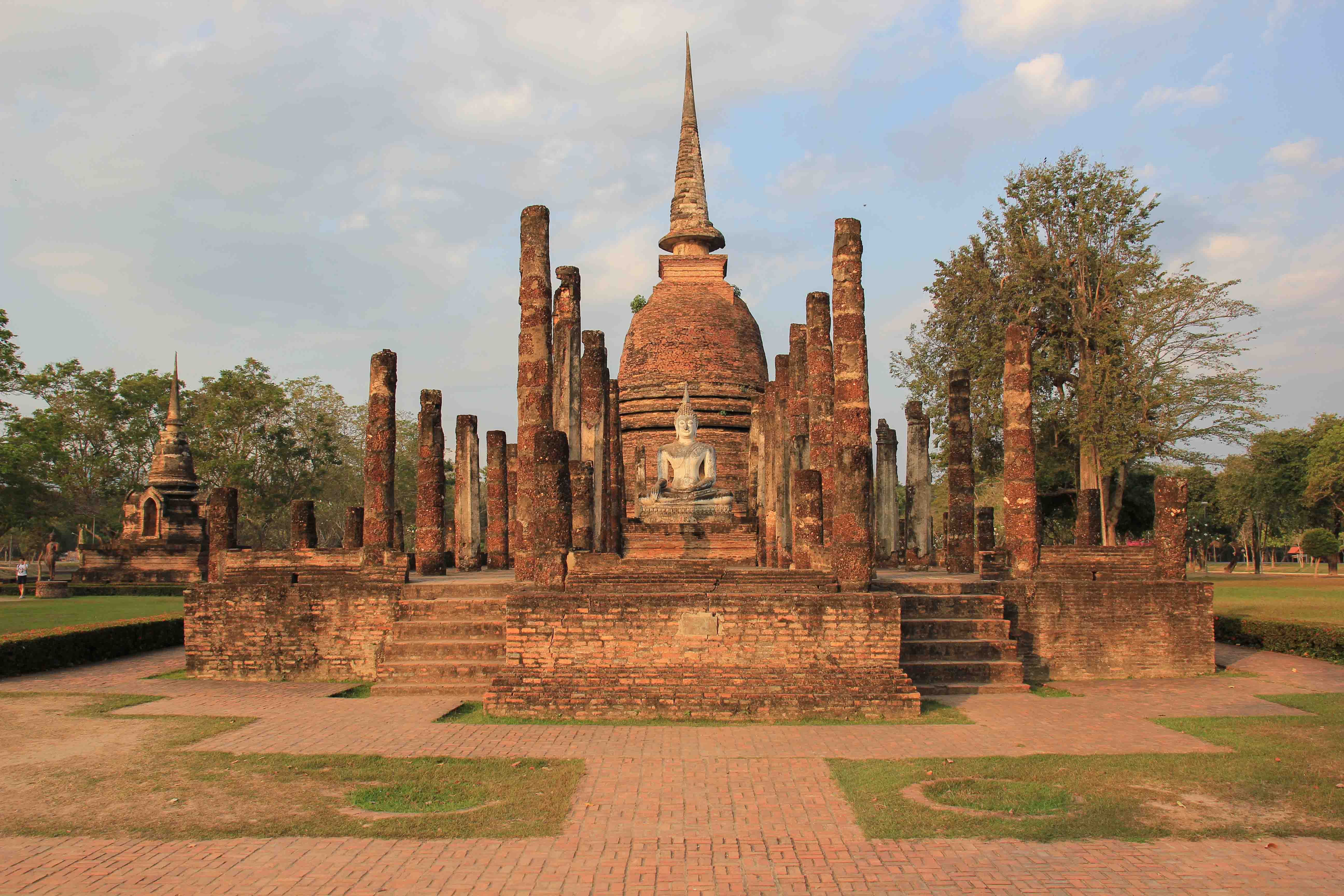 Young woman hipster backpacker traveling into Wat Mahathat temple in the  Sukhothai Historical Park contains the ruins of old Sukhothai, Thailand,  UNESCO world Heritage Site. Stock Photo